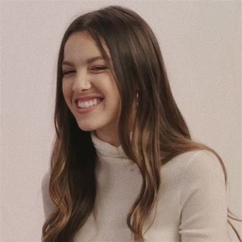 A Woman With Long Hair Smiling And Wearing A White Sweater Over A Black