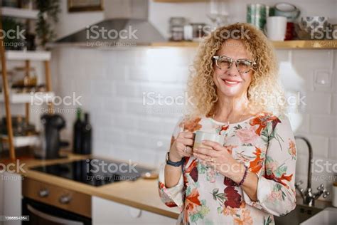 A Mature Woman Enjoys A Cup Of Tea And Looks Out The Window From Her