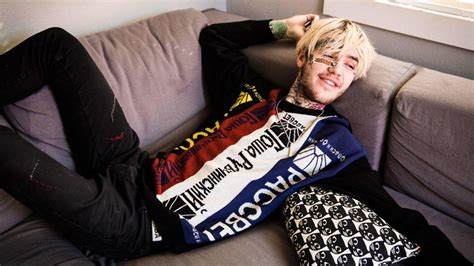 Lil Peep Is Lying Back On Couch Wearing Colorful Tshirt Having Tattoos