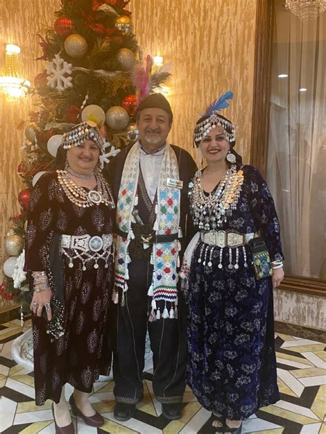 Three People Standing Next To Each Other In Front Of A Christmas Tree