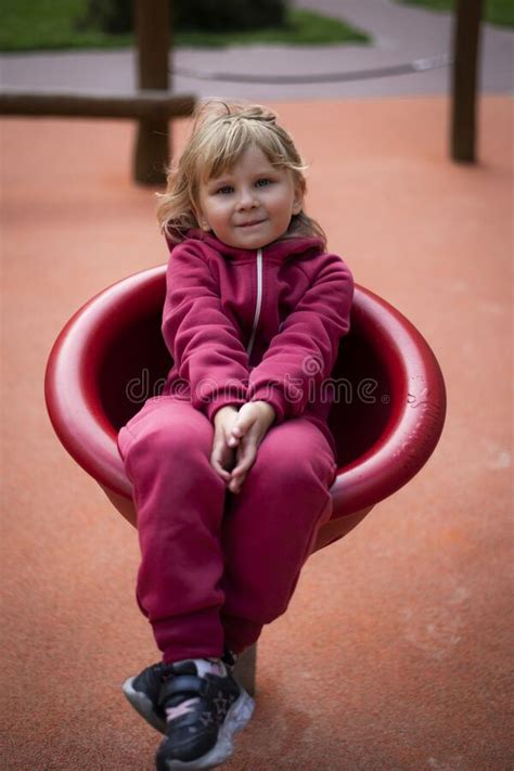 Little Girl 5 Years Old Blonde In Red Clothes Plays On The Playground
