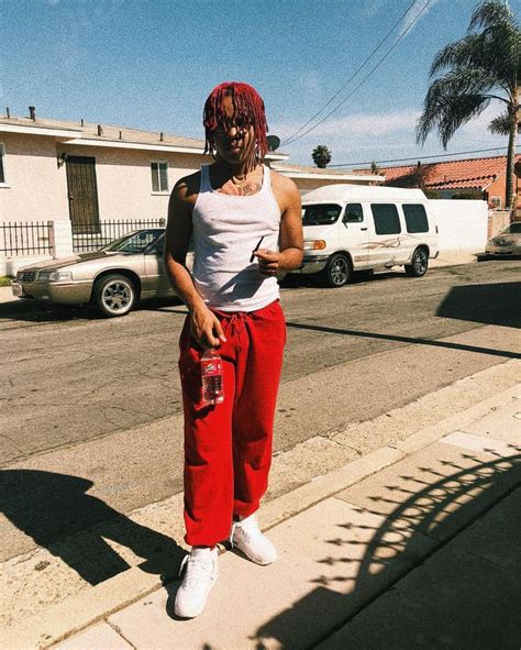 A Woman In Red Pants And White Tank Top Standing On The Sidewalk With