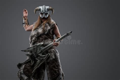 Crazy Viking From Past Playing Guitar Against Grey Background Stock
