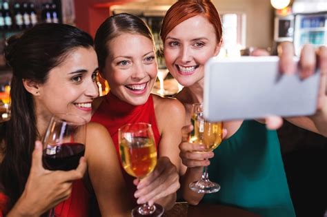 premium photo female friends taking selfie with wine glass in night club