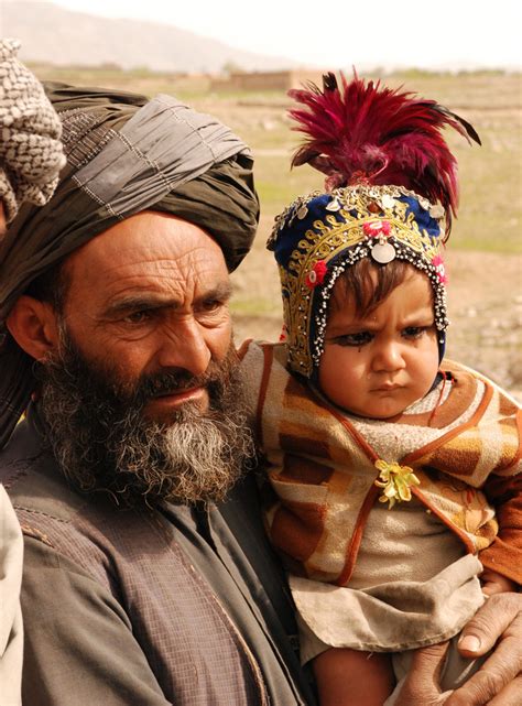 A Kuchi Nomad Holds A Child Wearing A Traditional Headdress In