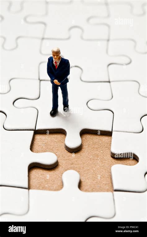 Businessman Miniature Figurine Standing On A Jigsaw Puzzle With A