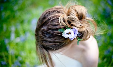 A Woman With Her Hair In A Bun And Flowers In Her Hair Is Looking Down At The Ground