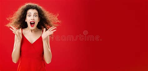 Portrait Of Surprised And Astonished Speechless Curly Haired Woman In Red Luxurious Dress