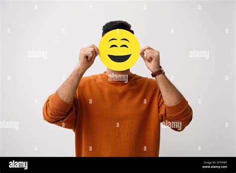 Man Hiding Emotions Using Card With Drawn Smiling Face On White