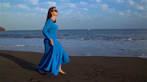 portrait of a woman in a beautiful blue dress on a black volcanic beach slow motion 23017478