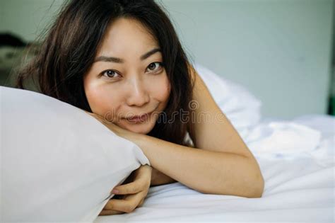 Young Asian Woman Sleeping In Bed With White Sheets Stock Image