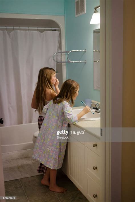 Caucasian Sisters Brushing Teeth In Bathroom Photo Getty Images