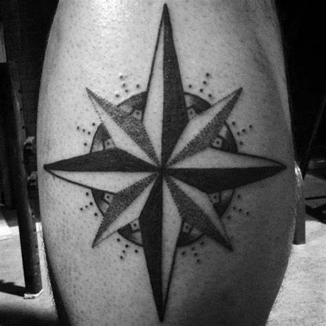 A Black And White Compass Tattoo On The Leg