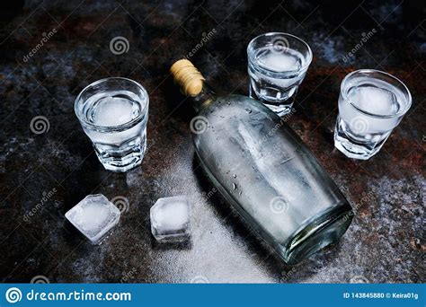 Bottle Of Vodka With Shot Glasses And Ice On Stone Background Stock