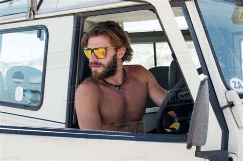 Shirtless Man Wearing Sunglasses Sitting In Off Road Vehicle Stock