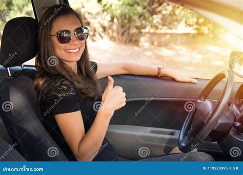 A Smiling Young Woman Sits In The Car With Thumbs Up Stock Image