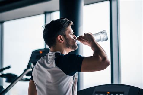 Premium Photo Man Drinking Water While Working Out On Treadmill In