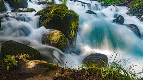 A Stormy Mountain River Flows Among Huge Stones In The Forest Slopes Of