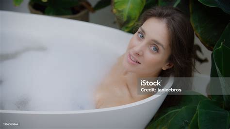 Young Woman Taking A Bubble Bath In Lush Green Garden Inside Her Bathroom Smiling To A Camera