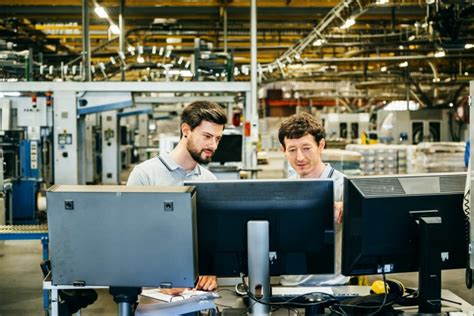 Engineers Behind Several Computer Monitors In A Huge Factory
