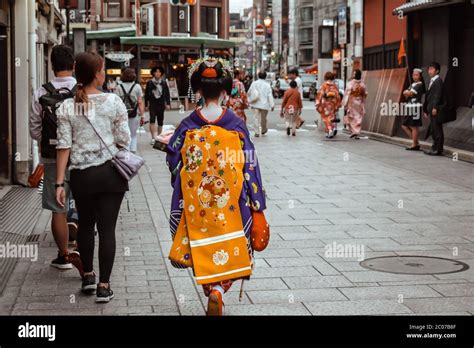 Japanese Geisha In A Colorful Blue And Yellow Kimono Walking Down A Street In Gion Kyoto Japan