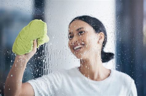 cleaning washing window and woman with cloth in hand to wipe water detergent and cleaning