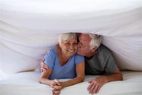Senior Man Kissing Woman Under Blanket On Bed Stock Image Image Of