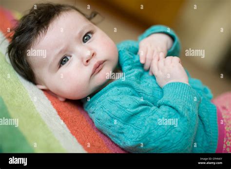 Beautiful Baby Girl With Blue Eyes And Brown Hair Lying On Floor At