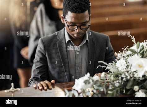 Funeral coffin, death and black man sad, grieving and mourning loss of