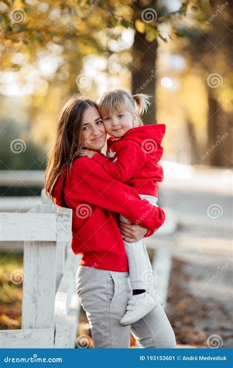 A Young Beautiful Mother Holds Her Cute Little Daughter In Her Hands During A Walk In The Autumn