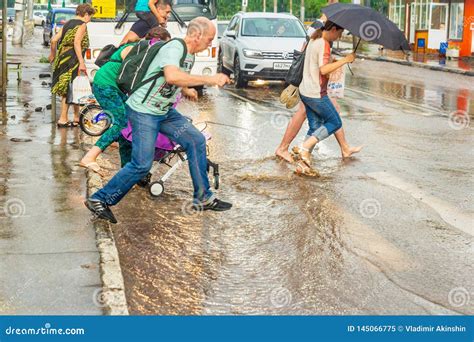 A Pedestrian Crosses The Road Through Deep Water After A Heavy Rainfall