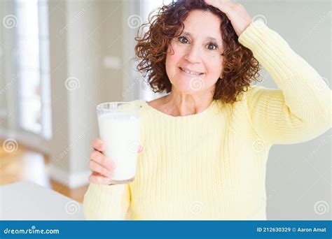 Senior Woman Drinking A Glass Of Fresh Milk Stressed With Hand On Head Shocked With Shame And