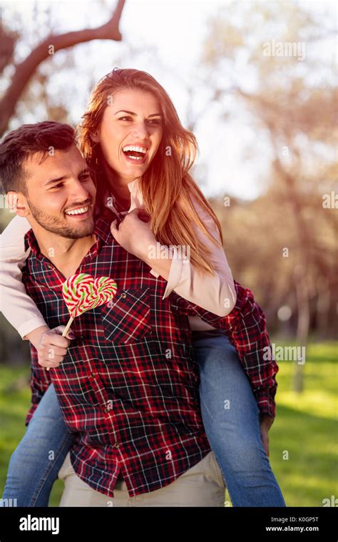 Portrait Of Smiling Handsome Man Giving Piggy Back To His Girlfriend In