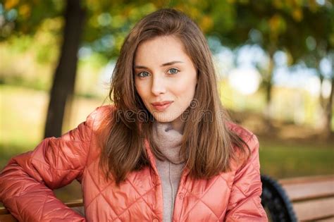 Close Up Portrait Of A Young Beautiful Brunette Woman In Coral Coat