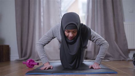 Portrait Of Muslim Woman In Hijab Pushing Up At Home Confident Strong
