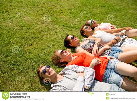Group Of Smiling Friends Lying On Grass Outdoors Stock Photo Image Of