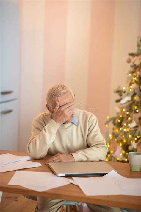 Elderly Man Sitting At The Table And Feeling Tired Stock Photo Image
