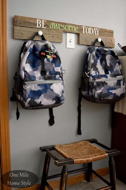 Two Backpacks Are Hanging On The Wall In Front Of A Stool And Sign That