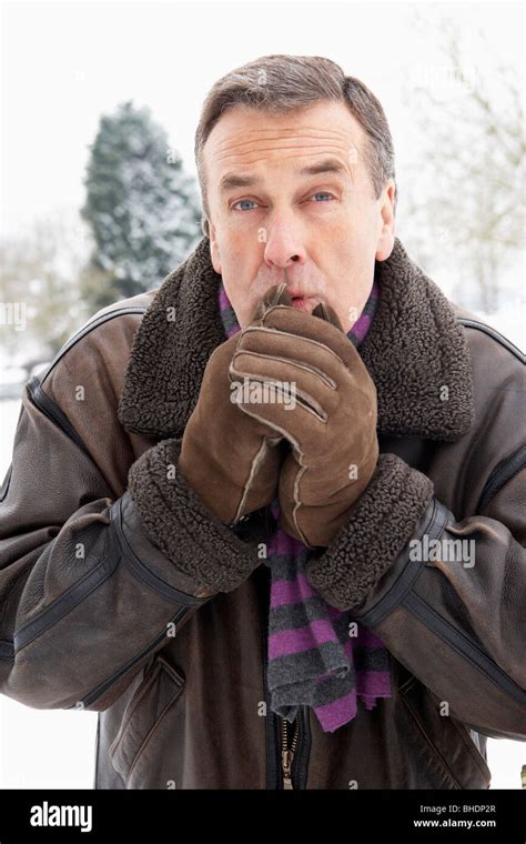 Senior Man Standing Outside In Snowy Landscape Warming Hands Stock