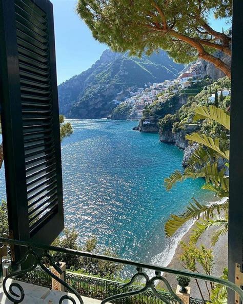 An Open Window Looking Out At The Ocean And Mountains From A Balcony