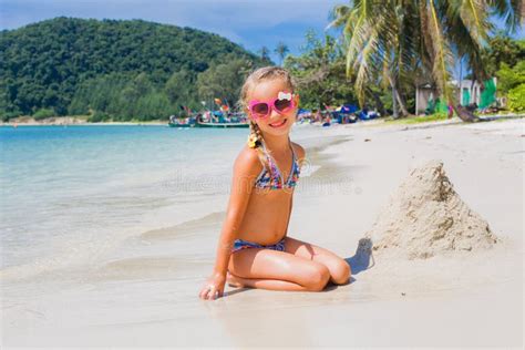 Милая маленькая девочка в солнечных очках и купальнике на пляже в рае морем Перемещение и