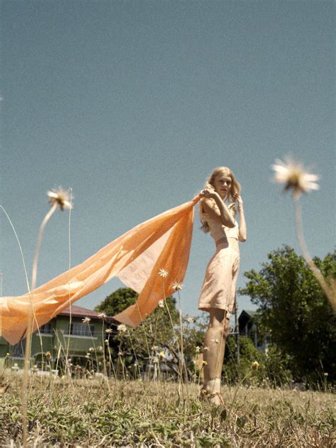 A Woman Standing On Top Of A Grass Covered Field Holding An Orange