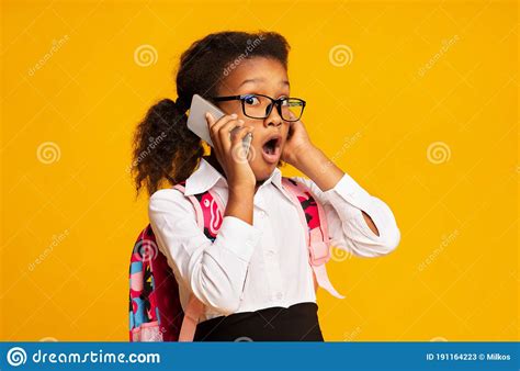 Shocked African Schoolgirl Talking On Cellphone Standing On Yellow