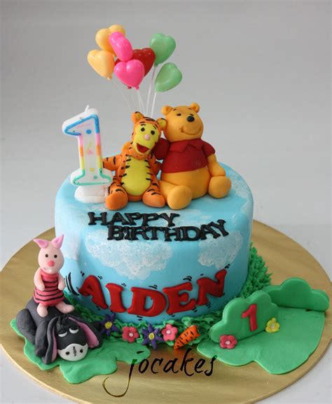A Winnie The Pooh Birthday Cake With Balloons