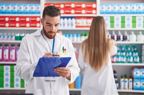Man And Woman Pharmacists Writing On Document At Pharmacy Stock Image