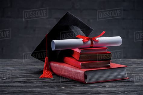 Stack Of Books With Diploma And Graduation Hat On Table Stock Photo