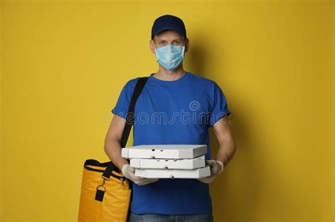 Courier In Protective Mask And Gloves Holding Pizza Boxes On Background