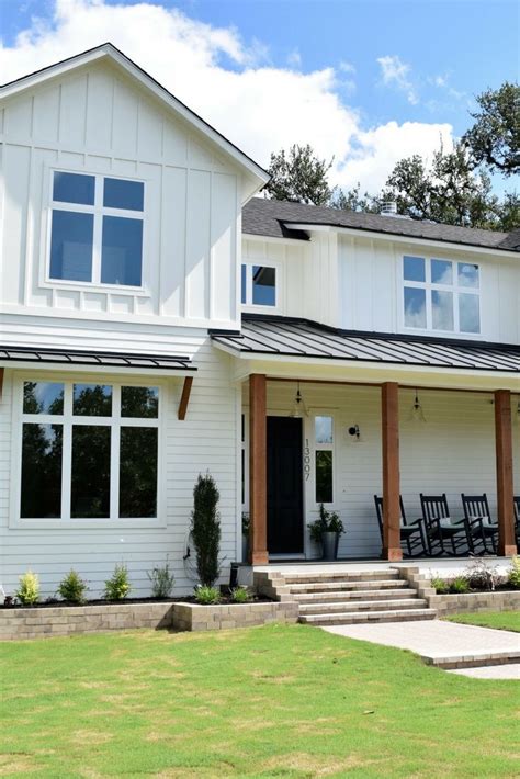 A Large White House With Two Porches And Chairs On The Front Lawn In