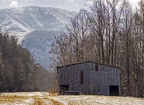 An Old Wooden Barn Sits Beneath A Snow Covered Mountain In The Smokies