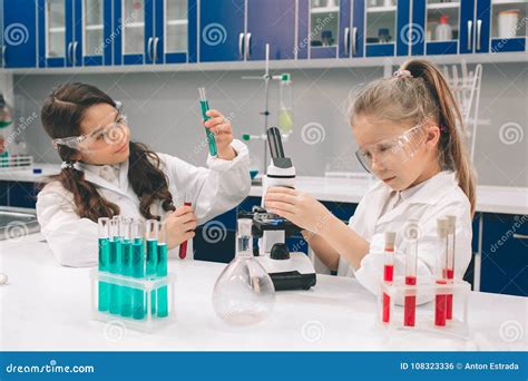 Two Little Kids In Lab Coat Learning Chemistry In School Laboratory